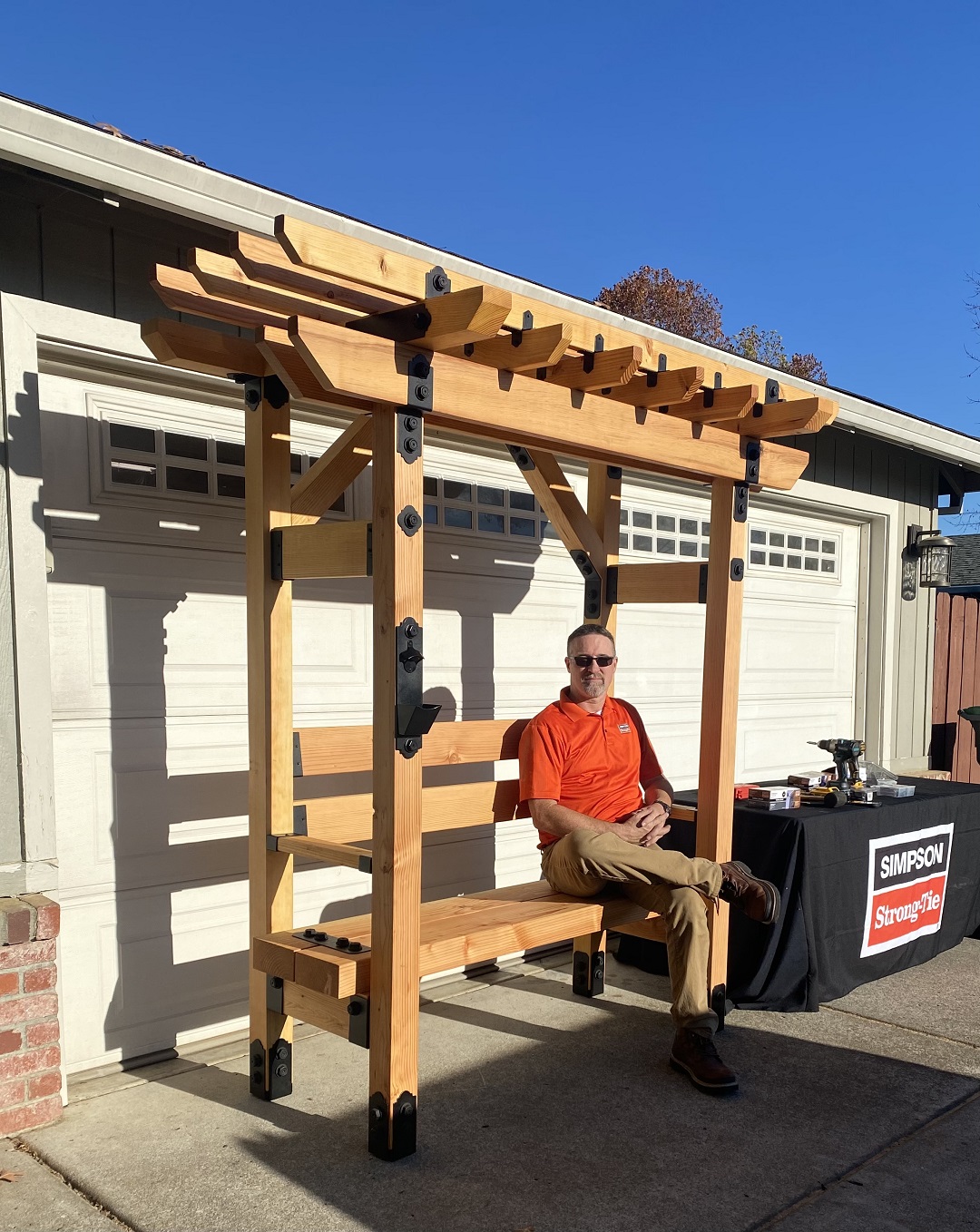 John Ross sitting on his newly built Outdoor Accents pergola bench