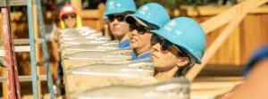 Women lift the frame of a house for Habitat for Humanity