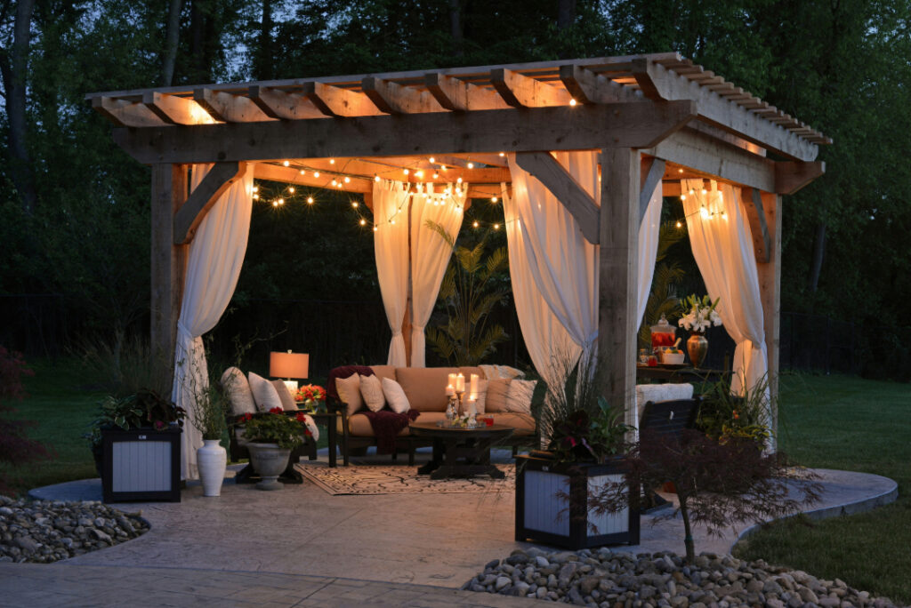 Pictured above is a gazebo with curtains covering a seated area lit by string lights.
