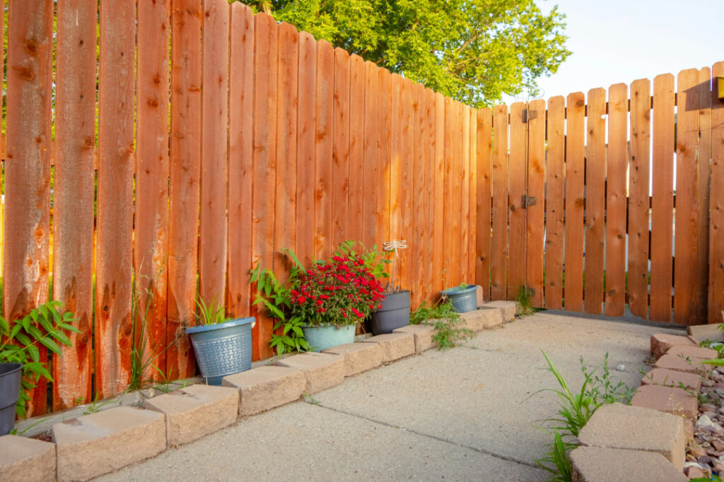 Pictured above is a brown fence on the perimeter of a backyard.