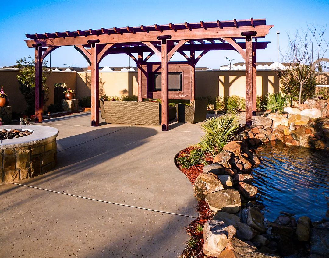 A large wooden pergola is built over a deck with ample seating.