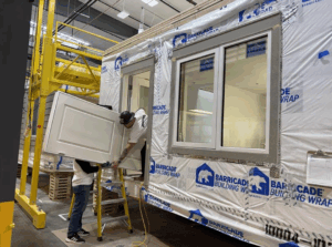 Using Simpson volunteers using teamwork to bring the doors into the modules for hanging.